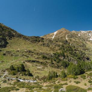 Mountain landscape with patches of snow under a blue sky.