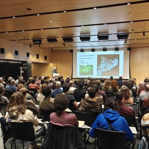 Presentació de Joan Pino, director del CREAF, davant de tota l'audiència de la jornada anual del Prismàtic. La sala està plena de gent.