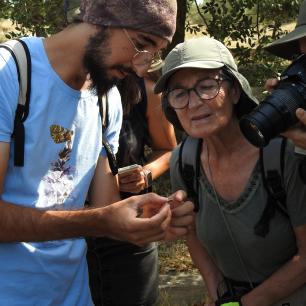 Persones voluntàries mirant una papallona que subjecten amb la mà i fotografien amb una càmera