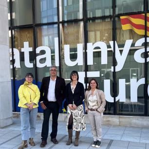 Group of four people standing in front of building with "Catalunya" text and flag.