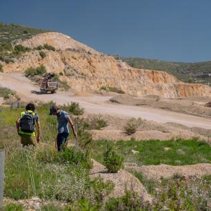 Two people walking past a quarry, truck, and a car.