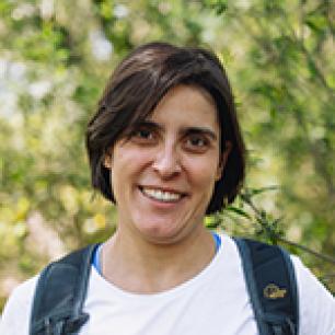 Smiling woman in a white shirt and backpack.