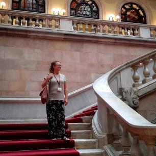 Annelies Broekman, investigadora del CREAF, a les escales de l'interior del Parlament de Catalunya, mirant a l'horitzó amb cara de felicitat i subjectant una bossa i una acreditació.