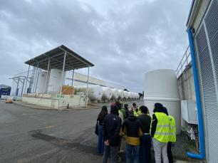 Group of people looking at white tanks at a facility.