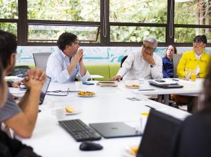 People in a meeting, around a white table.