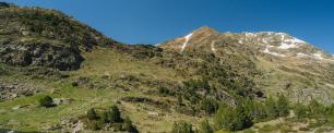 Mountain landscape with patches of snow under a blue sky.