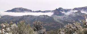 Snow-covered mountain range with cloudy sky.