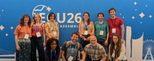 Group of people posing in front of a blue backdrop, smiling.