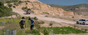 Two people walking past a quarry, truck, and a car.