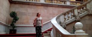 Annelies Broekman, investigadora del CREAF, a les escales de l'interior del Parlament de Catalunya, mirant a l'horitzó amb cara de felicitat i subjectant una bossa i una acreditació.