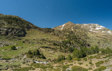 Mountain landscape with patches of snow under a blue sky.
