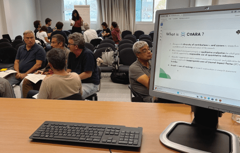 A group of people sitting, and a computer screen.