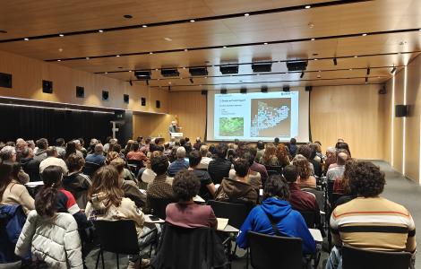 Presentació de Joan Pino, director del CREAF, davant de tota l'audiència de la jornada anual del Prismàtic. La sala està plena de gent.
