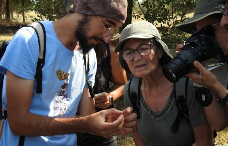 Persones voluntàries mirant una papallona que subjecten amb la mà i fotografien amb una càmera