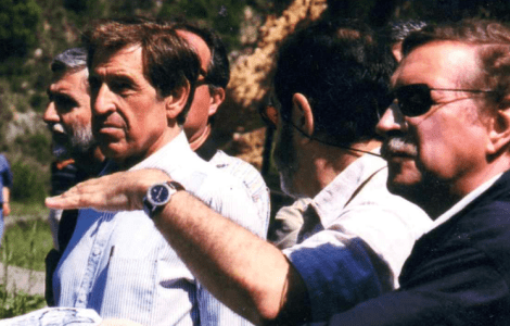 Men in a group, one pointing with his hand.