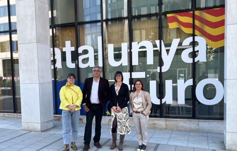 Group of four people standing in front of building with "Catalunya" text and flag.