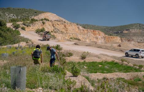 Two people walking past a quarry, truck, and a car.