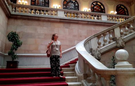 Annelies Broekman, investigadora del CREAF, a les escales de l'interior del Parlament de Catalunya, mirant a l'horitzó amb cara de felicitat i subjectant una bossa i una acreditació.