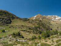 Mountain landscape with patches of snow under a blue sky.