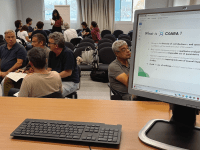 A group of people sitting, and a computer screen.