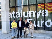 Group of four people standing in front of building with "Catalunya" text and flag.