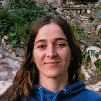 Woman with brown hair and a blue hoodie, smiling.