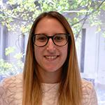 Woman with glasses and long blonde hair smiling at the camera.