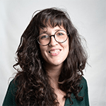 Smiling woman with curly hair wearing glasses.