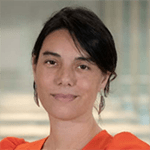 Woman with dark hair, wearing an orange top, smiles at the camera.