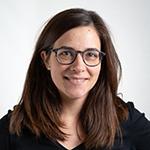 Woman with brown hair and glasses smiling at the camera.