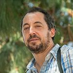 Man with brown hair and beard, wearing a plaid shirt.