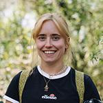 Blonde woman smiling, with trees in the background.