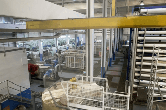 Inside a factory, large machinery and pipes.