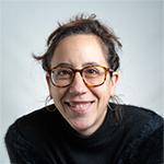 Woman smiling, wearing glasses, and a black sweater.