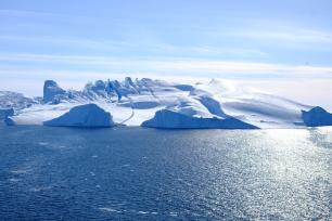 Iceberg in the ocean under a clear blue sky.