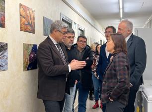 Group of people in a hallway looking at paintings on a wall.