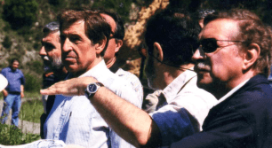 Men in a group, one pointing with his hand.