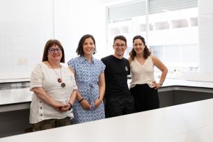 Four people smiling in a bright white laboratory.