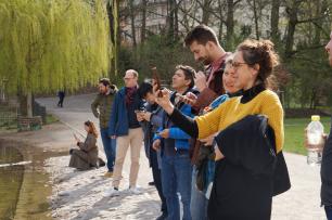 Un grupo de personas que miran algo cerca de un estanque, al aire libre.