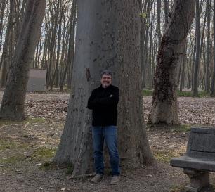 Man standing in front of a giant tree, arms crossed.