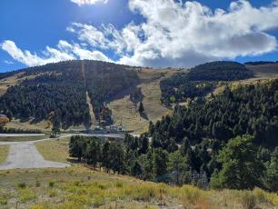Mountain ski slopes under a partly cloudy blue sky.