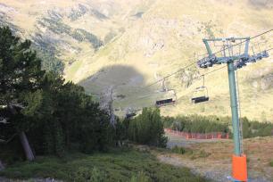 Ski lift with empty chairs over a mountain landscape.