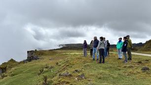 Group of people on a cliff with cloudy sky.