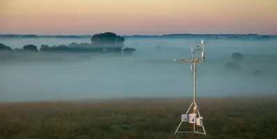 Weather station in a field with morning fog.